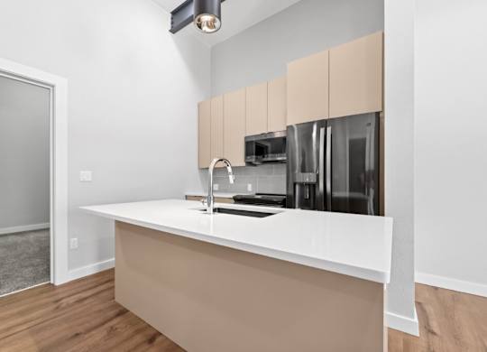 A kitchen with a white counter and beige cabinets at The Avenue Lofts Golden Apartments, Golden, CO, 80401