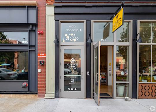 The front of a building with a grey facade and a glass door.