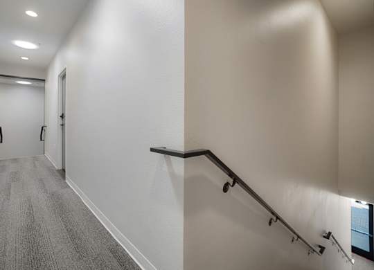 A hallway with a staircase and a carpeted floor at The Avenue Lofts Golden Apartments, Golden 80401