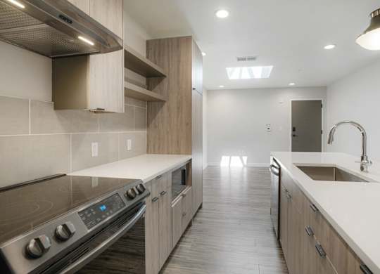 A modern kitchen with a stove top oven and a sink at The Avenue Lofts Golden Apartments, Golden, Colorado
