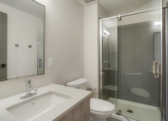 A modern bathroom with a sink, toilet, and shower at The Avenue Lofts Golden Apartments, Golden, CO