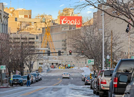 A Coors sign is on a building in a city at The Avenue Lofts Golden Apartments, Golden