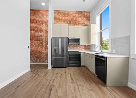 A kitchen with a red brick wall and wooden floors at The Avenue Lofts Golden Apartments, Golden