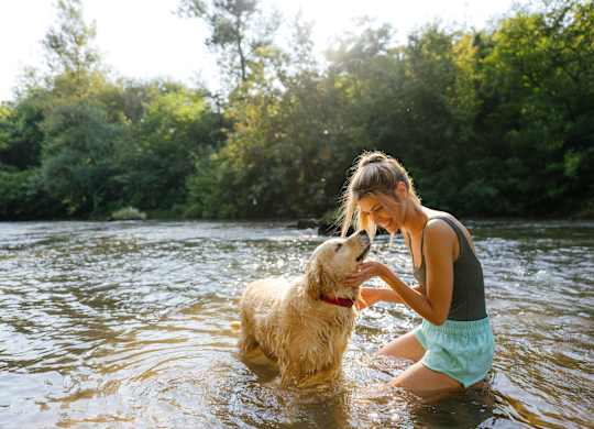 A woman is playing with her dog in the water.