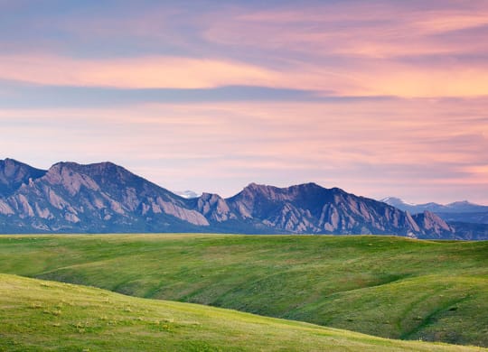 Landscape of grassy field with a mountain range at Brownstones at Palisade Park, Broomfield