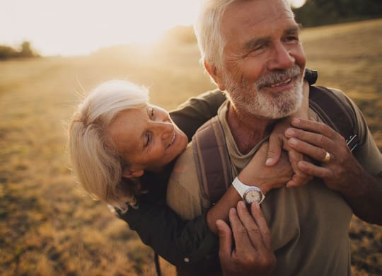 an older couple embraces in a field as the sun sets at Brownstones at Palisade Park,  Colorado