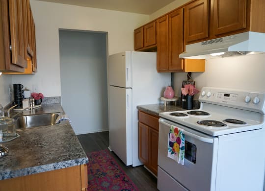 Kitchen with granite countertop, oven, refrigerator, sink, and wood cabinets, at Gale Gardens Apartments,