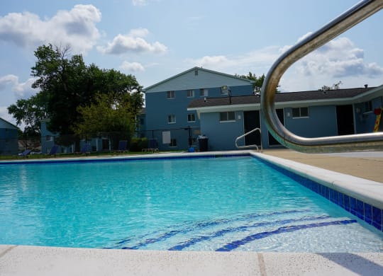 Swimming Pool Entry with pool chairs and apartment building, at Gale Gardens