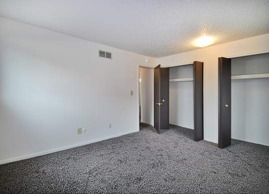 A room with a carpeted floor and three doors.