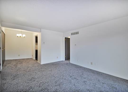 A large empty room with carpeted floor and white walls.