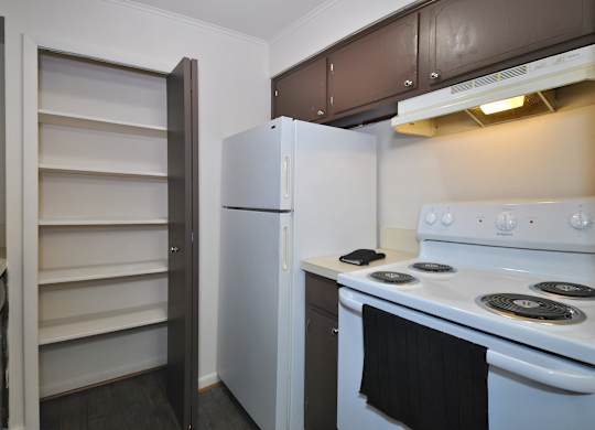 A white refrigerator and stove in a kitchen with brown cabinets.
