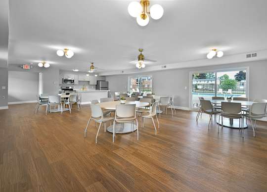 Resident clubhouse with a kitchen, seating, community tables, and bright natural light at Warren Woods Apartments in Warren, MI.