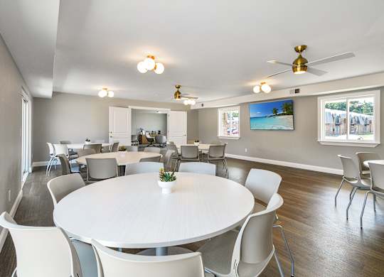 Resident clubhouse with a kitchen, seating, community tables, and bright natural light at Warren Woods Apartments in Warren, MI.