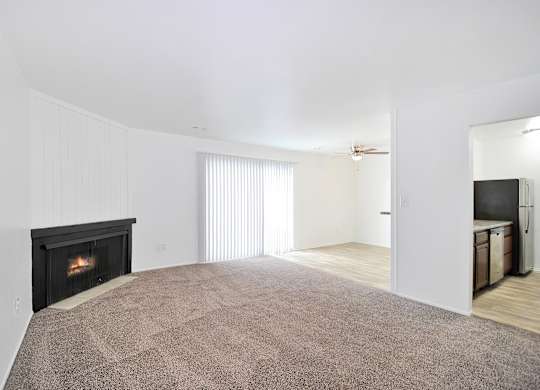 Spacious living room at Woodcrest Apartments in Westland, MI with neutral décor, plush carpeting, and large windows for natural light.