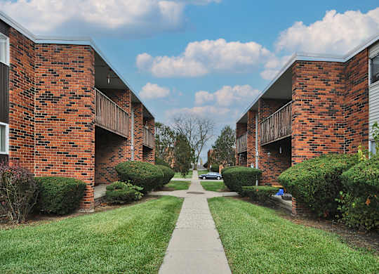 A long, narrow walkway separates two rows of red brick apartment buildings.