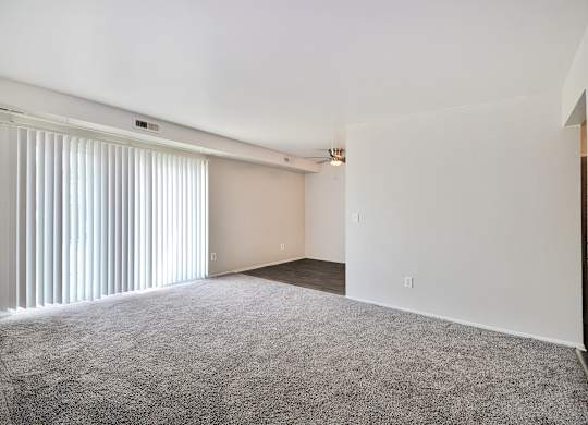 Spacious living room with large windows, neutral walls, and plush carpet at Warren Woods Apartments in Warren, MI.
