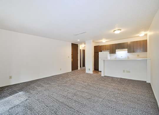 A spacious empty room with a carpeted floor and white walls.
