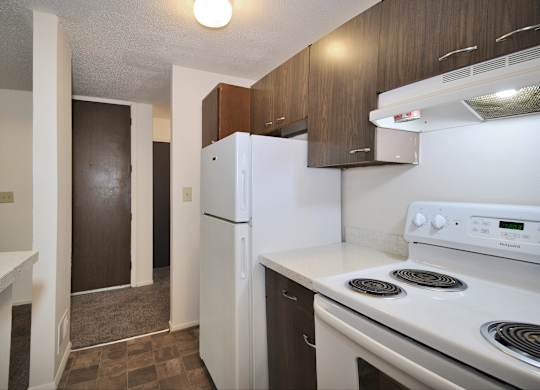 A white fridge and stove in a kitchen with brown cabinets.