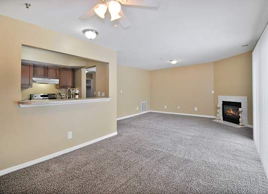 A spacious living room with a fireplace and a ceiling fan.