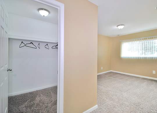 Comfortable bedroom at Woodcrest Apartments in Westland, MI featuring soft carpet flooring, a large closet, and large walk-in closets