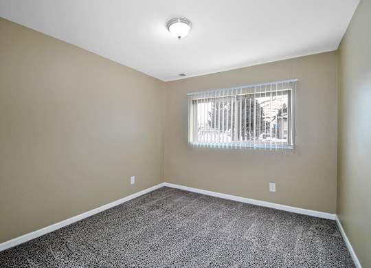 Comfortable bedroom at Woodcrest Apartments in Westland, MI featuring soft carpet flooring, a large closet, and peaceful natural light.