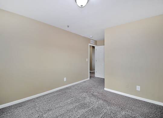 Comfortable bedroom at Woodcrest Apartments in Westland, MI featuring soft carpet flooring, a large closet, and peaceful natural light.