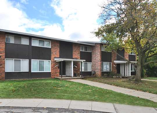 A brick apartment building with a tree in front.