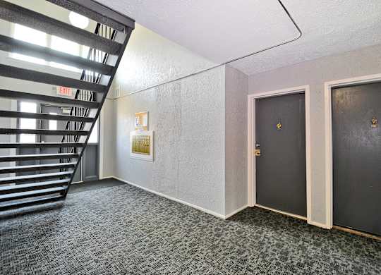 Hallway entrance to apartment with staircase, new carpeting, at Warren Woods Apartments in Warren, MI