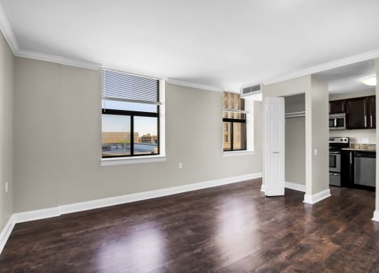 an empty living room with a window and a kitchen