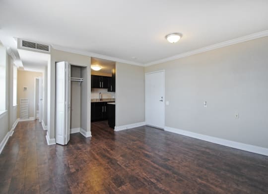 an empty living room with wood flooring and a kitchen