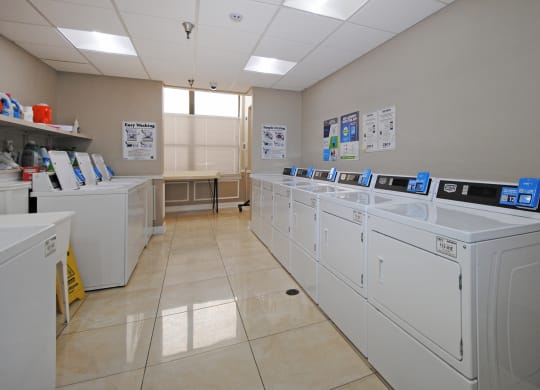 a row of washing machines in a laundry room with washers and dryers