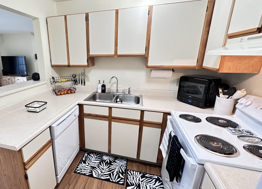an empty kitchen with white cabinets and a stove and sink