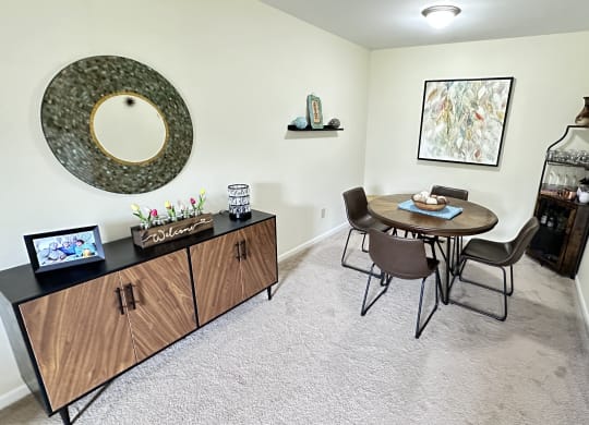 a dining room with a table and chairs and a wall mounted mirror
