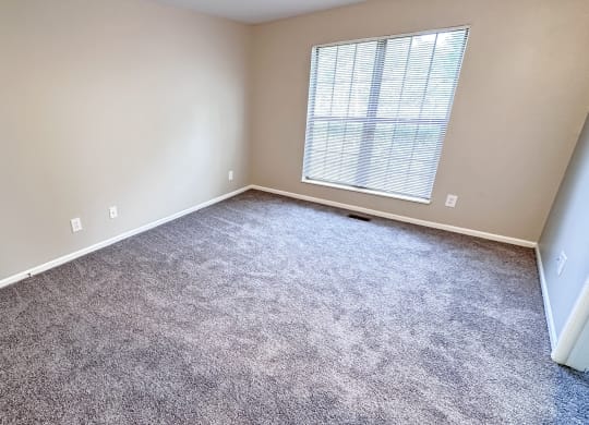 an empty room with carpet and a window