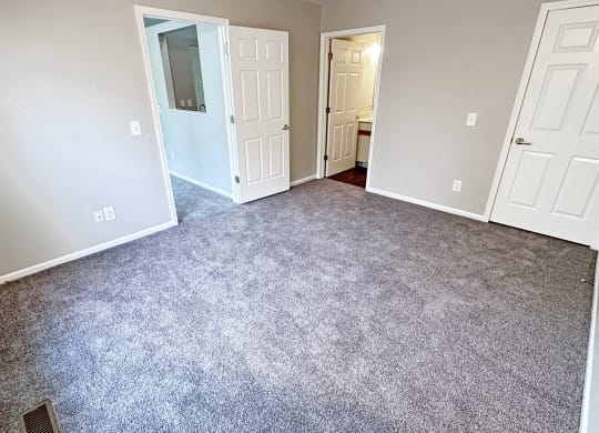 an empty room with a carpeted floor and white doors