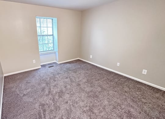 an empty room with carpet and a window