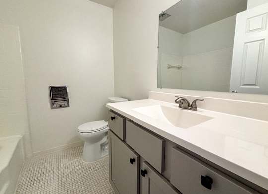 A white bathroom with a toilet, sink, and mirror.