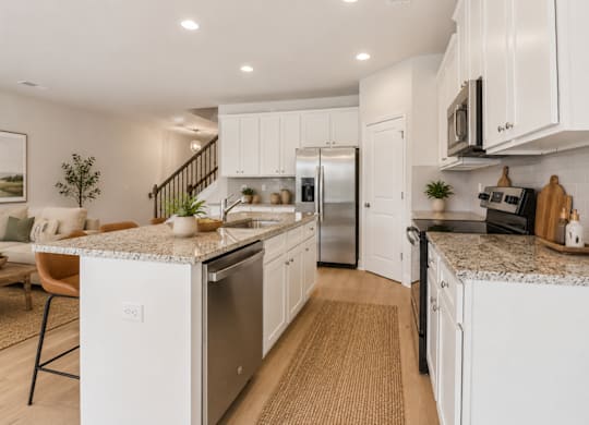 Spacious kitchen with an island, ample storage, stainless steel appliances and view into the living room.