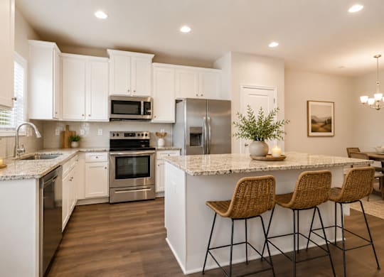 Spacious kitchen with an island, ample storage, stainless steel appliances and view into the living room.