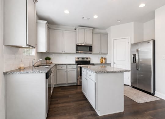 Spacious kitchen with an island, ample storage, stainless steel appliances and view into the living room.
