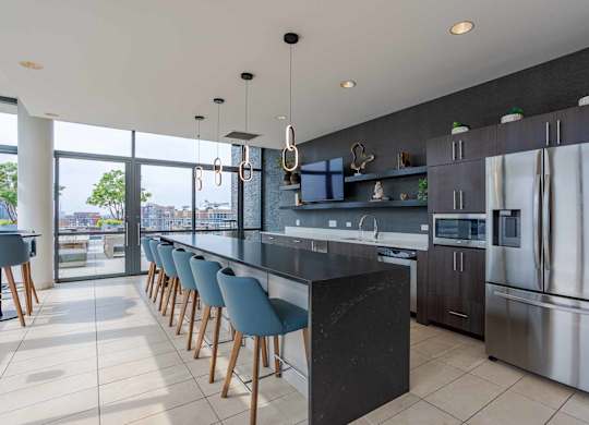 A modern kitchen with a long bar and stainless steel appliances.