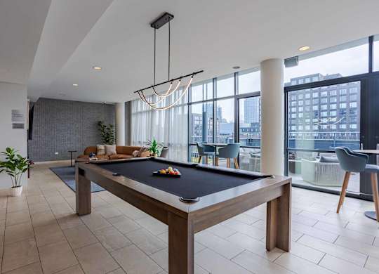 A pool table is in the middle of a room with a view of the city.