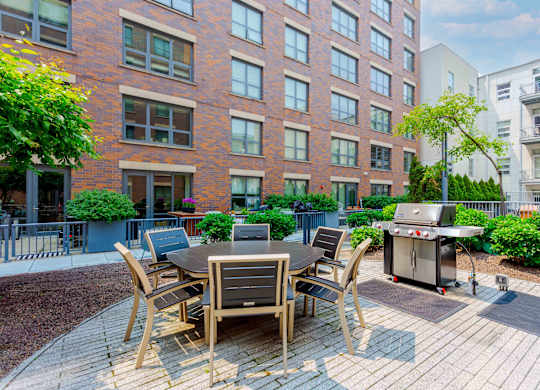 A patio with a table and chairs is surrounded by a brick building.