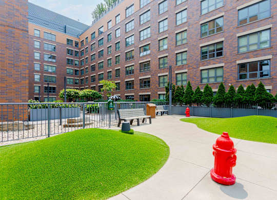 A red fire hydrant sits on a concrete walkway in front of a brick building.