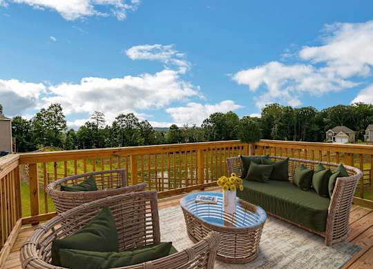 A wooden deck with a wicker sofa and table.
