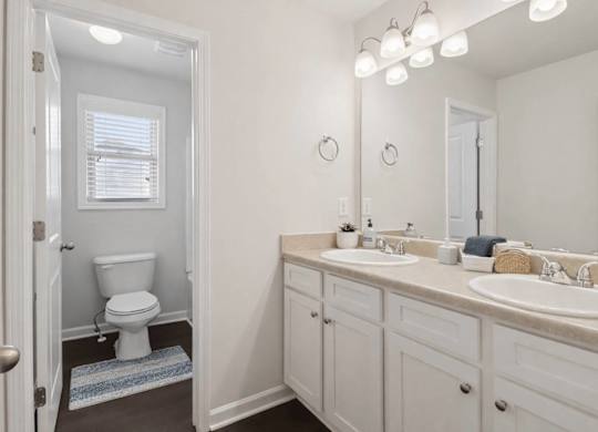 A white bathroom with a toilet, sink, and mirror.