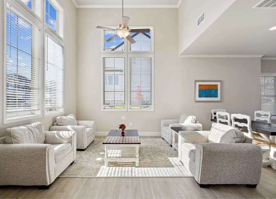 A living room with white furniture and a ceiling fan.