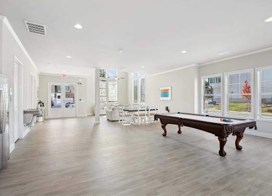 A spacious kitchen with a pool table and a refrigerator.