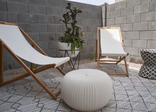 a patio with two chairs and a white ottoman and a mirror and plants at Novella Biltmore, Phoenix, AZ