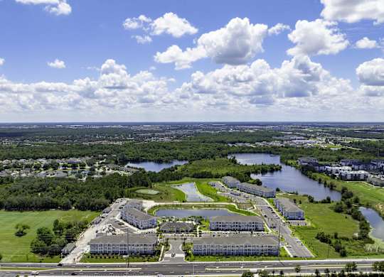 A large building complex sits in the middle of a green field with a river running through it.